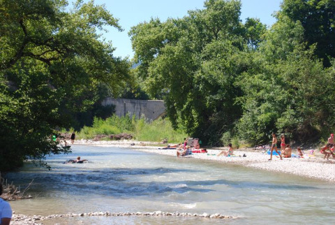 Des personnes se détendent et nagent près de la rivière au Flower Camping la Pinède, Auvergne-Rhône-Alpes.