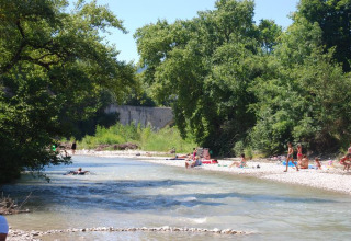 Personas descansan y nadan en el río en Flower Camping la Pinède, Auvergne-Rhône-Alpes, Francia.