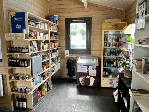 Small grocery store at Flower Camping Provence Vallée with shelves of goods and a fridge in Provence, France.