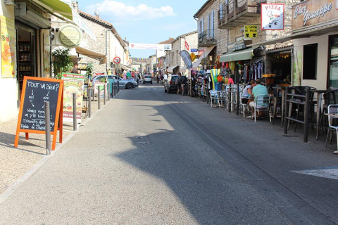 Vista stradale a Lalevade d'Ardèche, Francia, con caffè all'aperto, negozi locali e persone sedute.