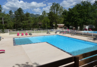 Piscine extérieure avec transats et arbres autour au Flower Camping la Pinède en Auvergne-Rhône-Alpes, France.