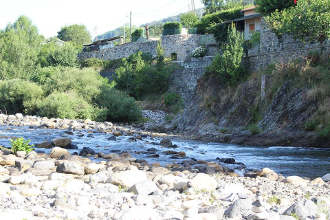 Rocky riverbank and flowing water at Camping Paradis Family des Issoux, Auvergne-Rhône-Alpes, France.