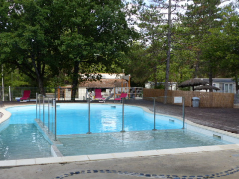 Piscine extérieure avec transats et arbres au Flower Camping la Pinède en Auvergne-Rhône-Alpes, France.