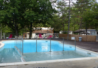 Udendørs swimmingpool med liggestole og træer på Flower Camping la Pinède i Auvergne-Rhône-Alpes, Frankrig.