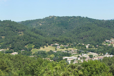 View of Camping Paradis Family des Issoux in Auvergne-Rhône-Alpes, France, surrounded by green hills.