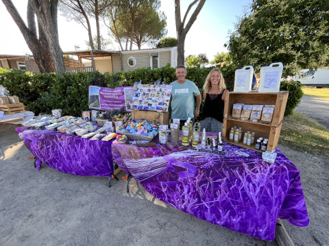 Ein Paar steht hinter einem Marktstand mit Lavendelprodukten auf dem Flower Camping Provence Vallée in Frankreich.
