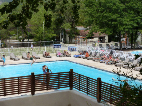 Piscine extérieure avec transats et vacanciers au Flower Camping la Pinède, parc de vacances en Auvergne-Rhône-Alpes.