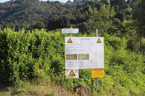 Hinweisschilder, Warnhinweise und grüne Büsche im Camping Paradis Family des Issoux, Auvergne-Rhône-Alpes, Frankreich.