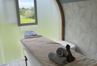 Sala luminosa de tratamientos con camilla y ventana en Flower Camping Provence Vallée, Provenza, Francia.