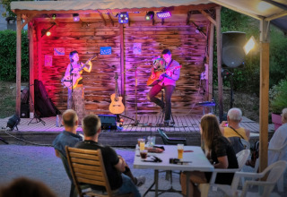 Esibizione musicale acustica dal vivo al Flower Camping Provence Vallée, Francia, con spettatori seduti all’aperto.