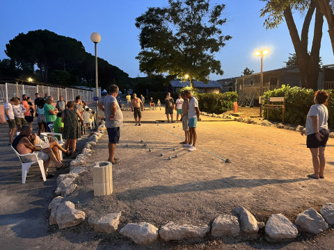 Avondsfeer op Flower Camping Provence Vallée met mensen die pétanque spelen onder verlichting.