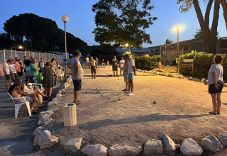 Sera al Flower Camping Provence Vallée, persone che giocano a pétanque sotto le luci artificiali.