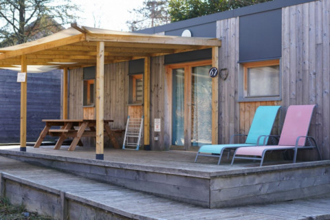 Wooden chalet with covered porch, picnic table, and two loungers, accessible for limited mobility guests.