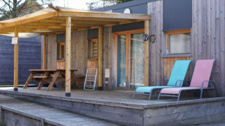 Wooden chalet with covered porch, picnic table, and two loungers, accessible for limited mobility guests.