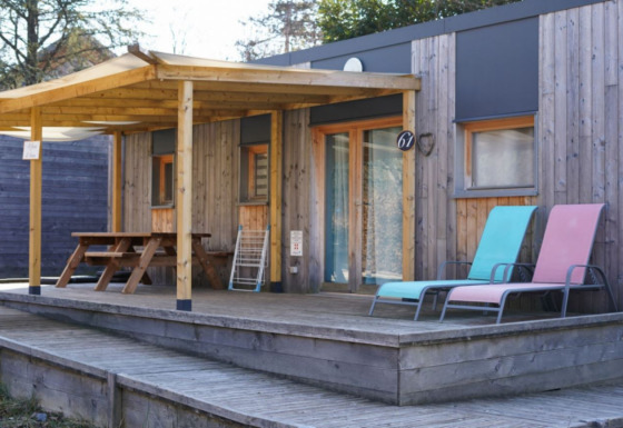 Wooden chalet with covered porch, picnic table, and two loungers, accessible for limited mobility guests.