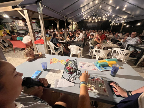 Aftenstemning med folk, der spiller bingo under et overdækket område i Flower Camping Provence Vallée, Frankrig.