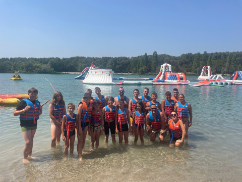 Gruppe mit Schwimmwesten vor Wasserpark und See im Flower Camping Provence Vallée, Frankreich.