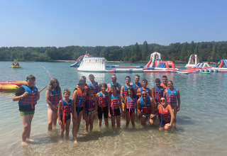 Gruppe mit Schwimmwesten vor Wasserpark und See im Flower Camping Provence Vallée, Frankreich.