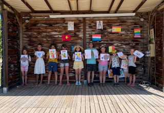 Kinder präsentieren ihre Zeichnungen auf einer Holzbühne im Flower Camping Provence Vallée in Südfrankreich.