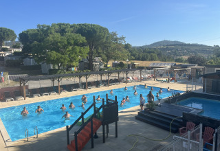 Personas disfrutan la piscina exterior en Flower Camping Provence Vallée, parque vacacional en Provence, Francia.