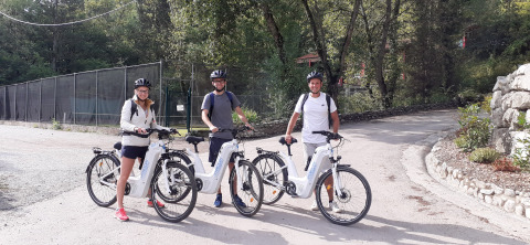 Trois adultes en casques profitent d'une balade en vélos électriques à Flower Camping la Pinède, en France.