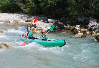 Two people paddle a green kayak through a rocky river near Die, Auvergne-Rhône-Alpes, France.