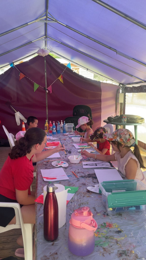 Enfants et adultes peignent ensemble à une longue table sous une tente au Flower Camping Provence Vallée.