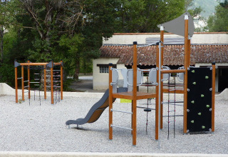 Zona de juegos con estructura para escalar y tobogán en Flower Camping la Pinède, parque vacacional, Francia.