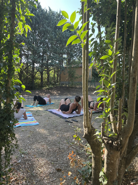 Personas practicando yoga al aire libre sobre esterillas rodeados de árboles en Flower Camping Provence Vallée.