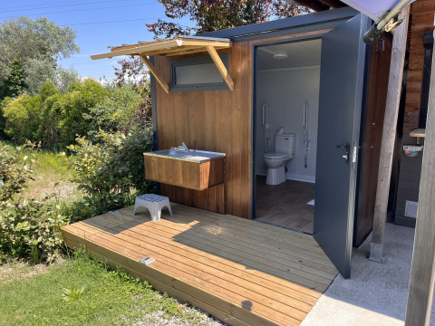 Accessible restroom with outdoor sink and wooden deck at Flower Camping Provence Vallée in Provence, France.