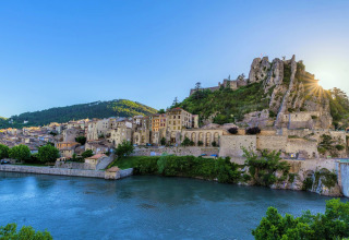 View of the village and castle by the river at Flower Camping Provence Vallée in Provence-Alpes-Côte d’Azur, France.