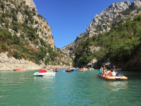 Menschen genießen das Paddelbootfahren auf einem türkisfarbenen Fluss im Tal bei Flower Camping Provence Vallée.