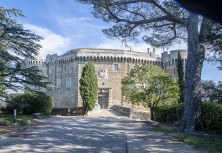 Foto de un castillo histórico de piedra rodeado de árboles en Flower Camping la Pinède, Auvergne-Rhône-Alpes, Francia.