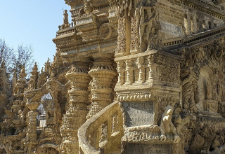 Two children admire an intricate stone structure in sunlight at Flower Camping la Pinède, France.