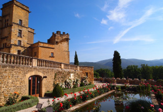 Castello di pietra con giardino fiorito e stagno, tra le colline della Provenza, Francia.