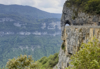 Bjergrigt landskab nær Die, Auvergne-Rhône-Alpes, Frankrig, med en vej tunneleret gennem klippen.