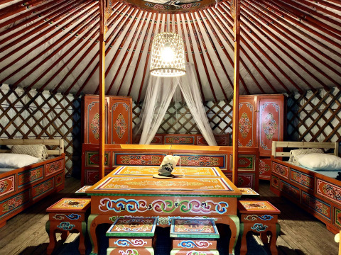Interieur van een traditionele Mongoolse yurt met kleurrijke houten meubels en bedden in Frankrijk.
