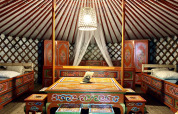 Interno di una tradizionale yurta mongola con mobili in legno decorati e letti colorati in Francia.