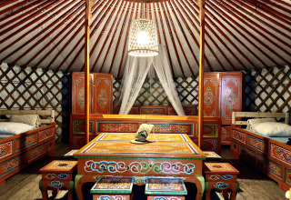 Interieur van een traditionele Mongoolse yurt met kleurrijke houten meubels en bedden in Frankrijk.