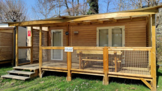 Außenaufnahme einer gemütlichen Glamping-Unterkunft mit Veranda und Sitzbank in natürlicher Umgebung.