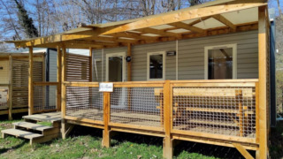 Stacaravan CONFORT 30m², een modern houten verblijf met overdekte veranda in een groene, natuurlijke omgeving.