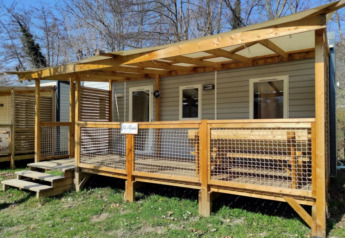 Stacaravan CONFORT 30m², moderno bungalow in legno con veranda coperta in un contesto naturale.