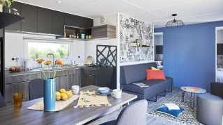 Sala de estar y cocina moderna y acogedora en Paradijs Luxe Stacaravan con decoración colorida y elegante.