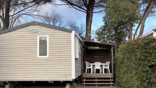 Mobile Home ECO Lodgia mit Terrasse, weißen Stühlen, Kinderfahrrad und Fußball auf grünem Rasen.