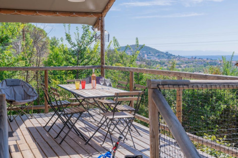 Holzterrasse im Lodgehut op palen bei Flower Camping Provence Vallée mit Blick auf Landschaft und Berge.