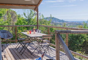 Wooden terrace at Lodgehut op palen in Flower Camping Provence Vallée, overlooking landscape and hills.