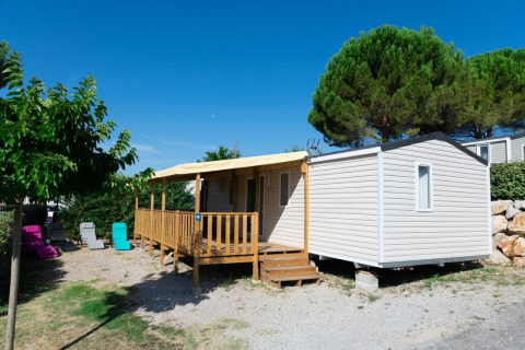 Premium Mobile Home 4 slaapkamers, luxe chalet met houten terras, ligstoelen en omringd door groen.