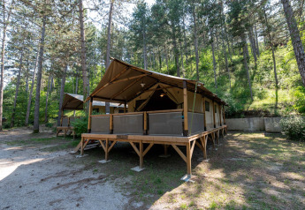 Safari telt Lodge Insolite Pinède 46m² omgivet af høje træer i en fredelig skovcampingplads.