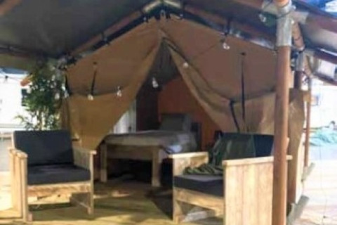 Interieur van de Lodge ‘Insolite Bivak’ safaritent bij Flower Camping la Pinède met stoelen en bed.