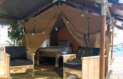 Interieur van de Lodge ‘Insolite Bivak’ safaritent bij Flower Camping la Pinède met stoelen en bed.